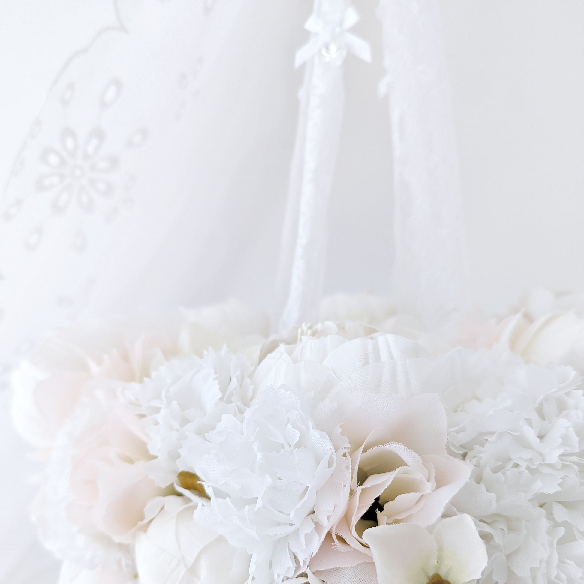 Blush pink balloon hanging beneath a wreath of creamy florals and dangling crystals—luxury nursery mobile design.