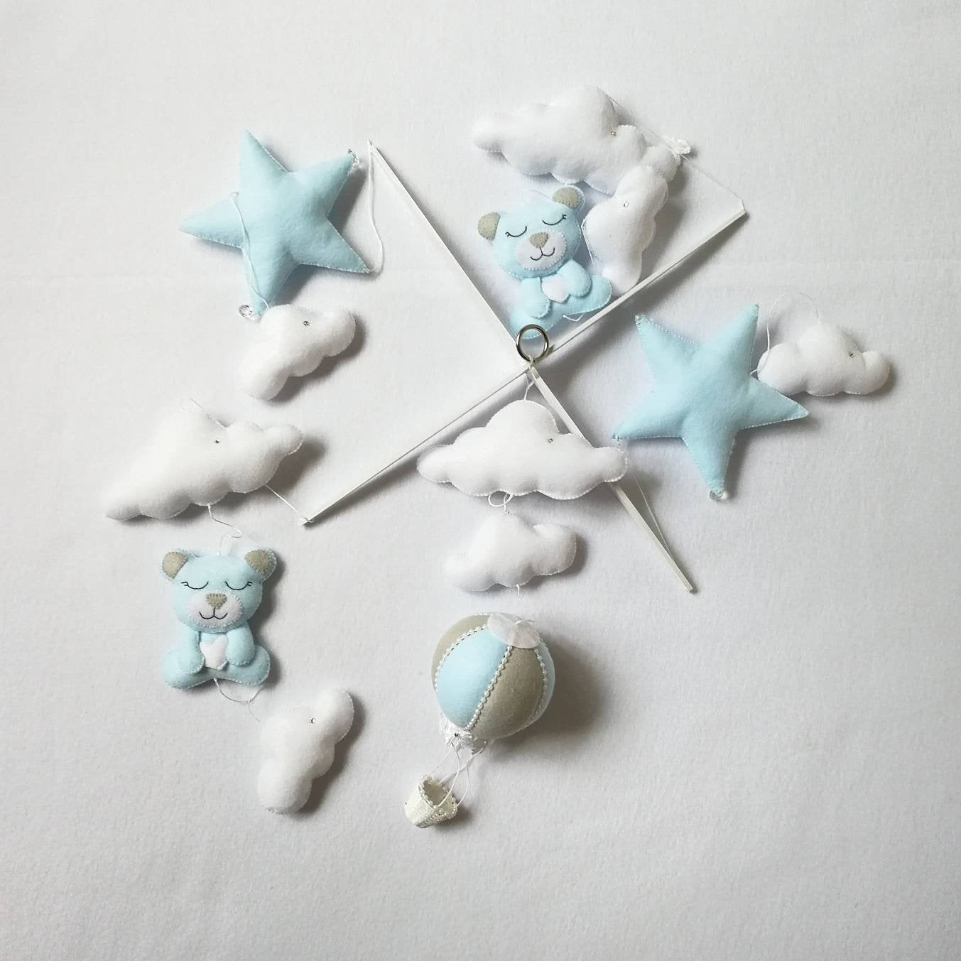 Overhead view of a mobile layout with blue stars, white clouds, teddies, and balloons 

