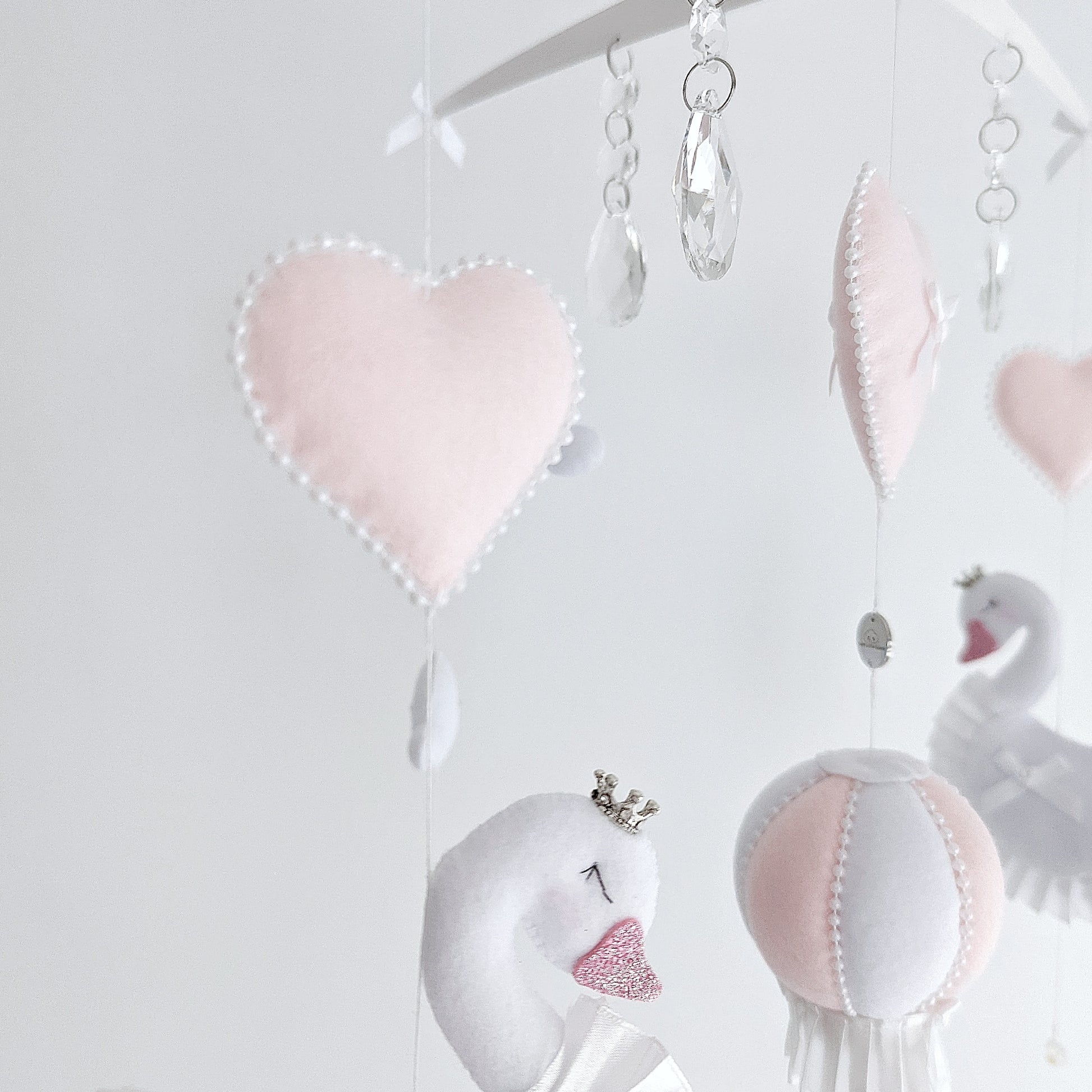 Collector-worthy mobile with graceful swans, heart motifs, and a blush-toned hot air balloon.