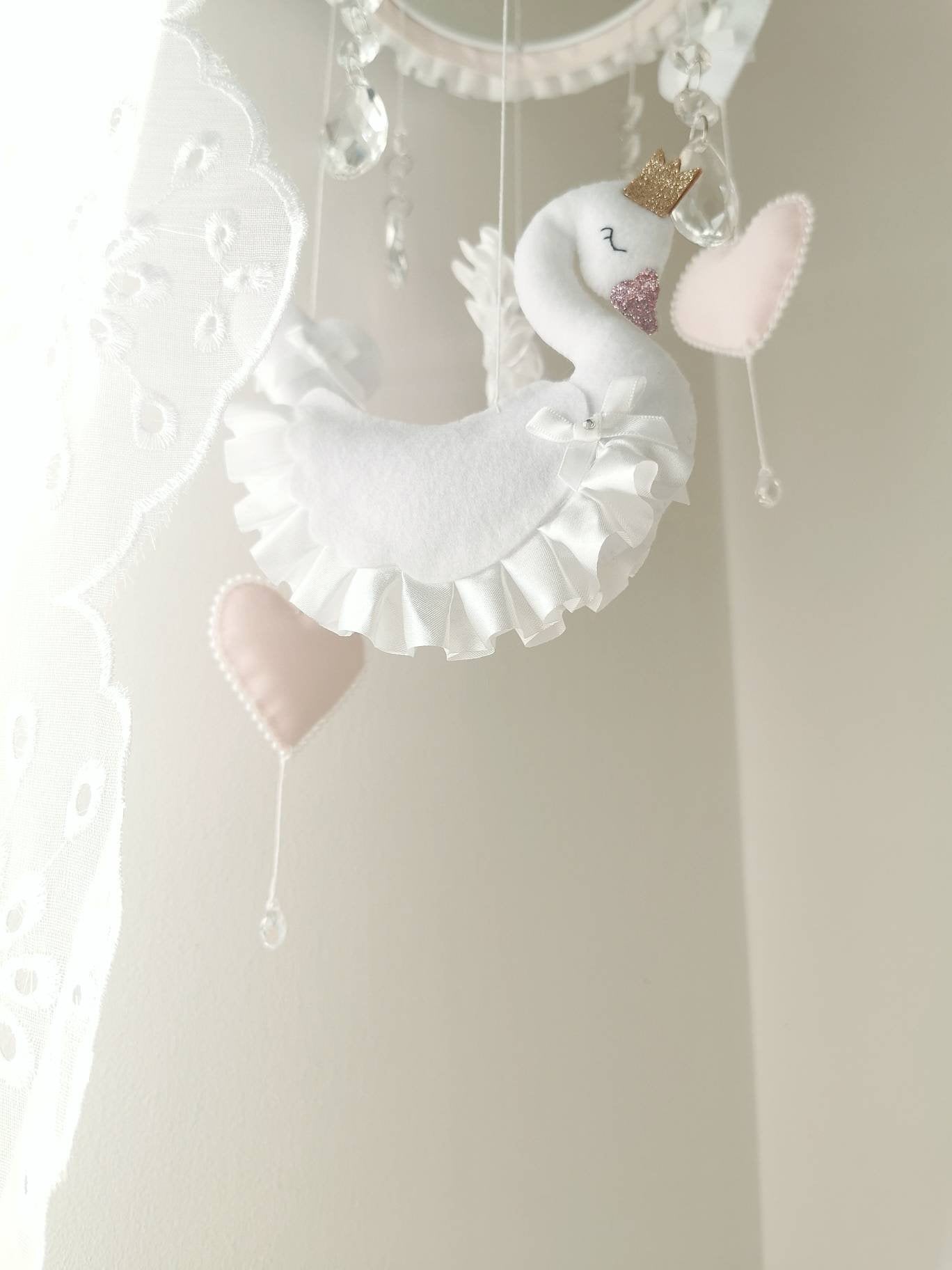 Elegant swan baby mobile decorated with hanging hearts and clear crystal drops, adding a magical touch to the nursery.