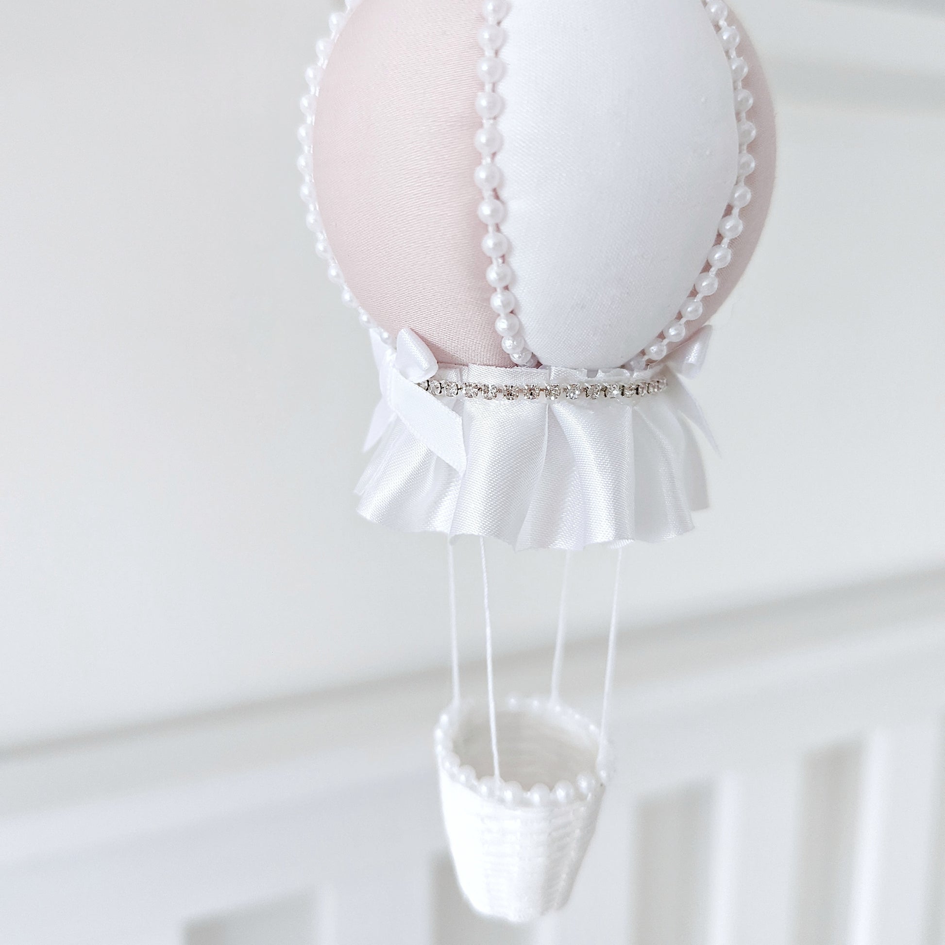 Elegant nursery mobile with cascading crystals, ivory roses, and a handmade balloon in soft pink and white.