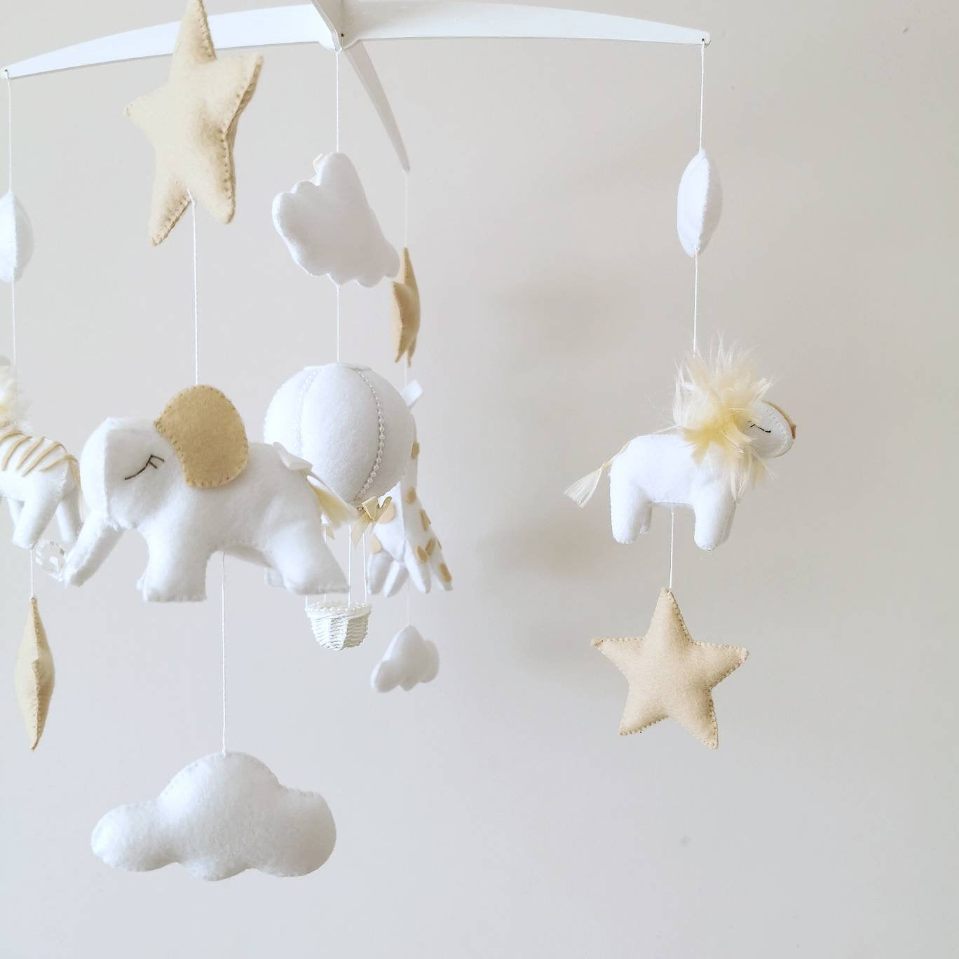Stars and clouds made of soft felt create a celestial lullaby, perfect for a peaceful, neutral nursery filled with wonder and luxury.