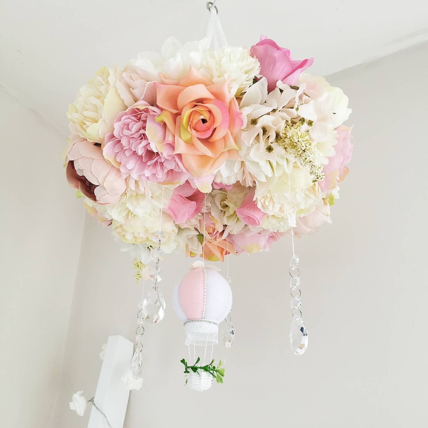 Romantic floral crown baby mobile with peonies, hydrangeas, and crystal accents surrounding a hot air balloon.