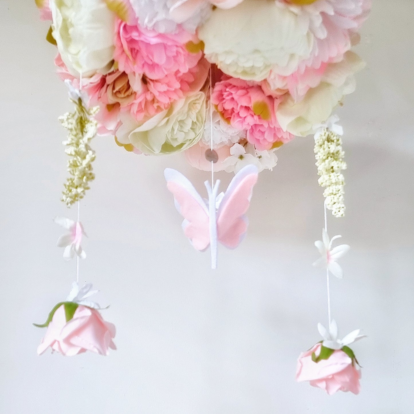Handcrafted mobile with soft trailing flowers, 3D butterfly, and realistic florals in ivory, blush, and peach tones.