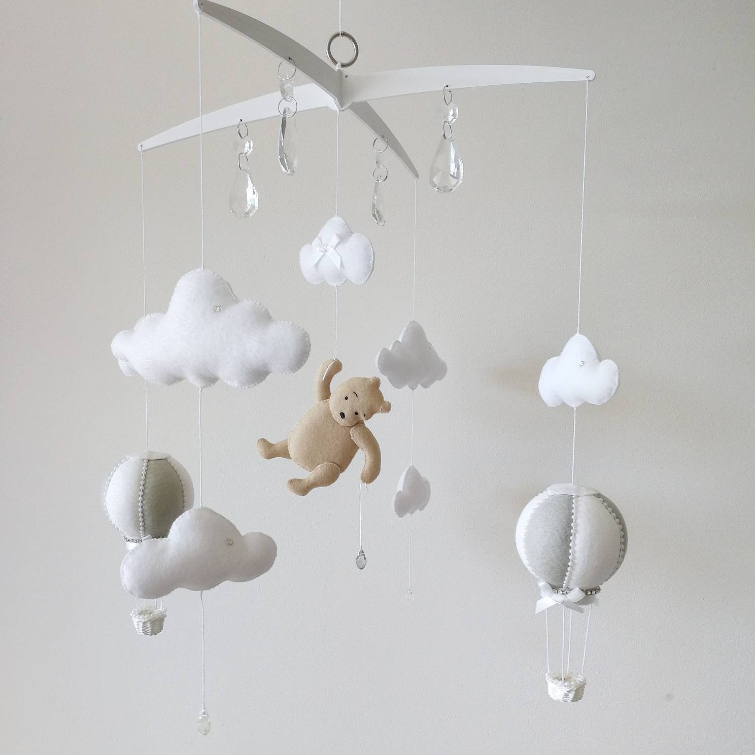 Neutral tones and soft textures create a calming scene where a little bear floats gently above a peaceful baby room

