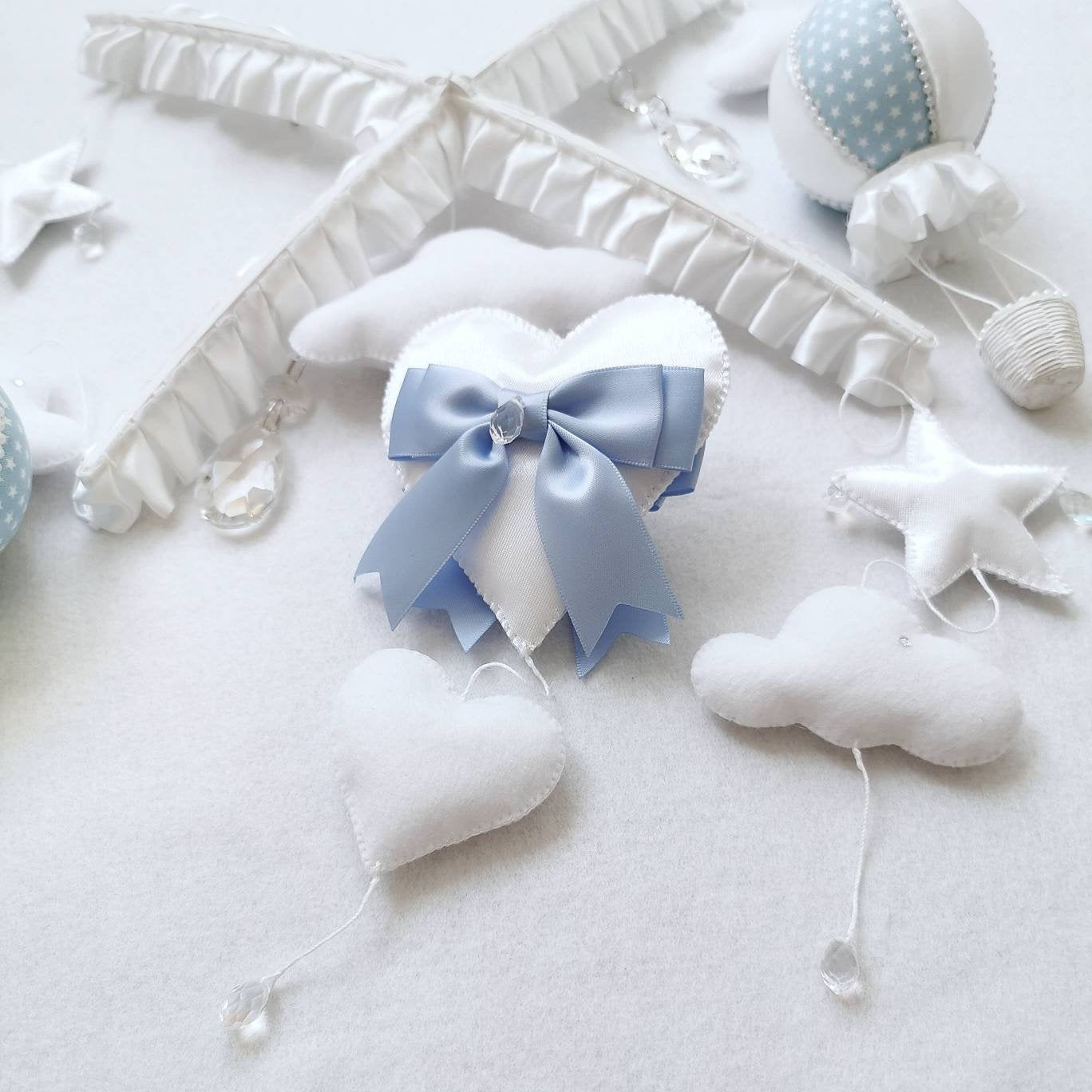 Flat lay of a baby mobile set with blue satin bow, balloons, stars, and clouds. Perfect baby shower gift