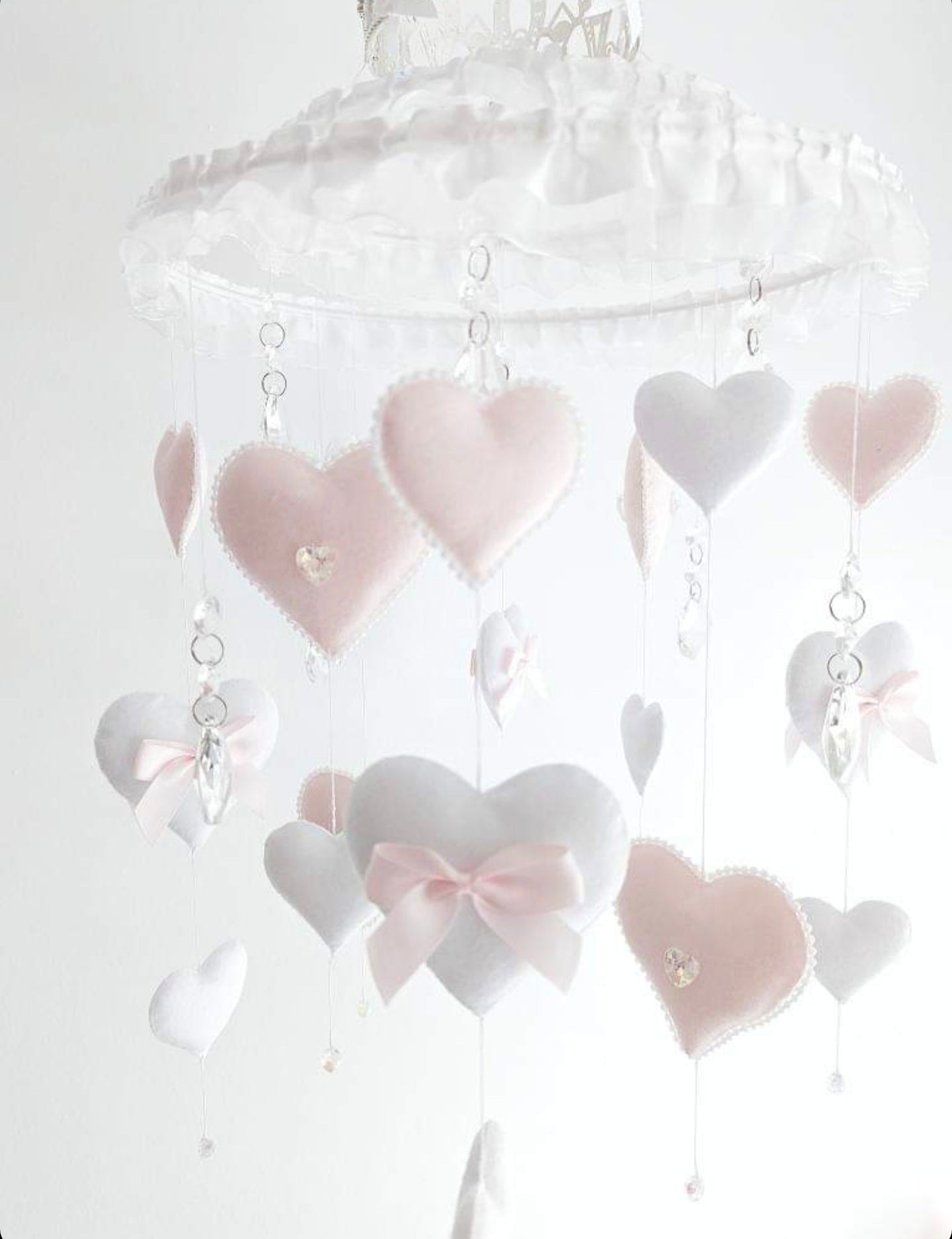 Handmade nursery mobile with felt hearts, bows, crystal drops, and a sparkling crown—perfect for a royal baby space.