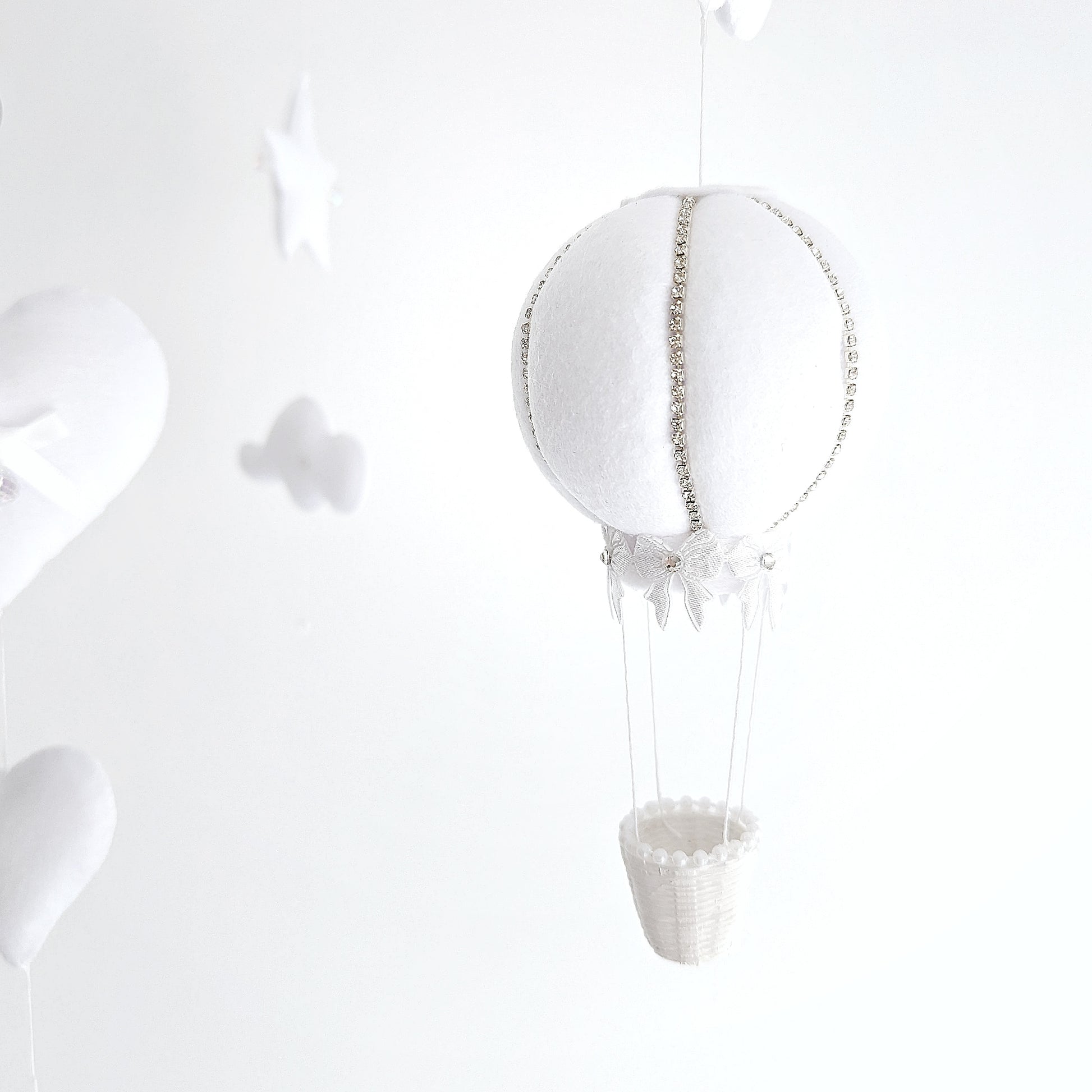 Neutral-toned baby mobile with soft hot air balloons and delicate felt clouds, ideal for a luxury unisex nursery.
