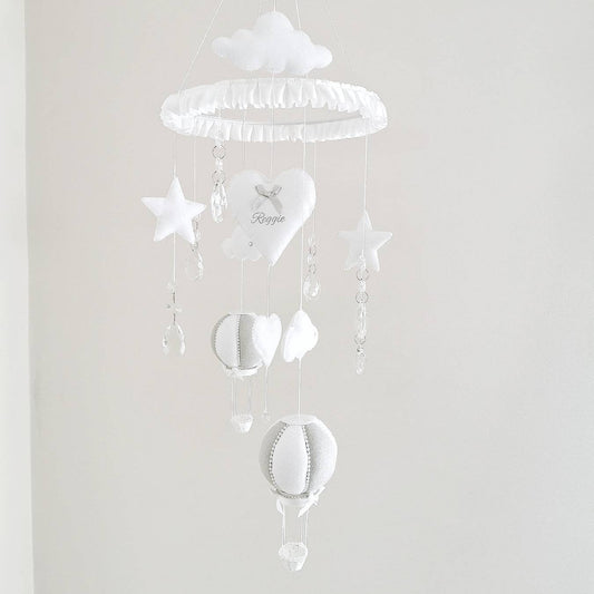 Luxury personalised baby mobile in soft white with embroidered heart, stars, clouds, and hot air balloons.
