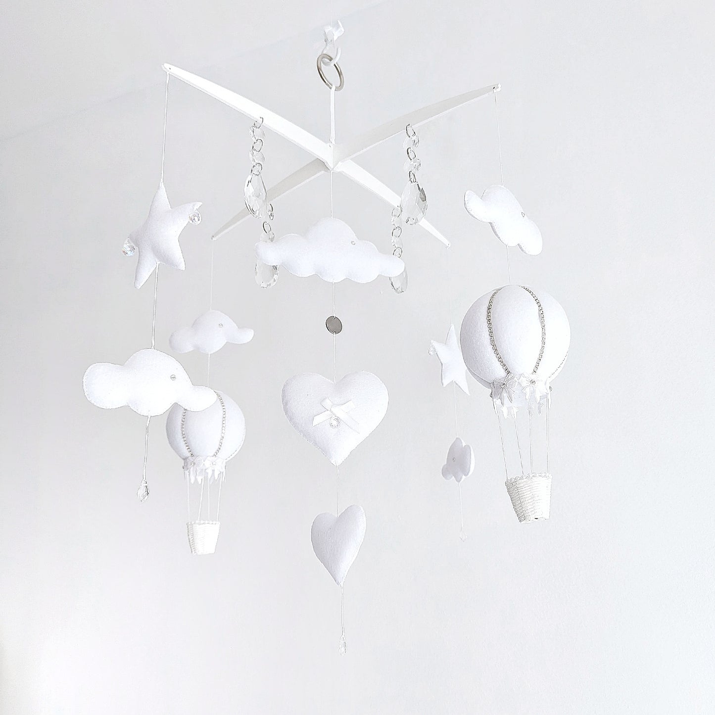 Elegant white nursery mobile featuring handcrafted hot air balloons, star details, and crystal drops for a soft sky-inspired look.