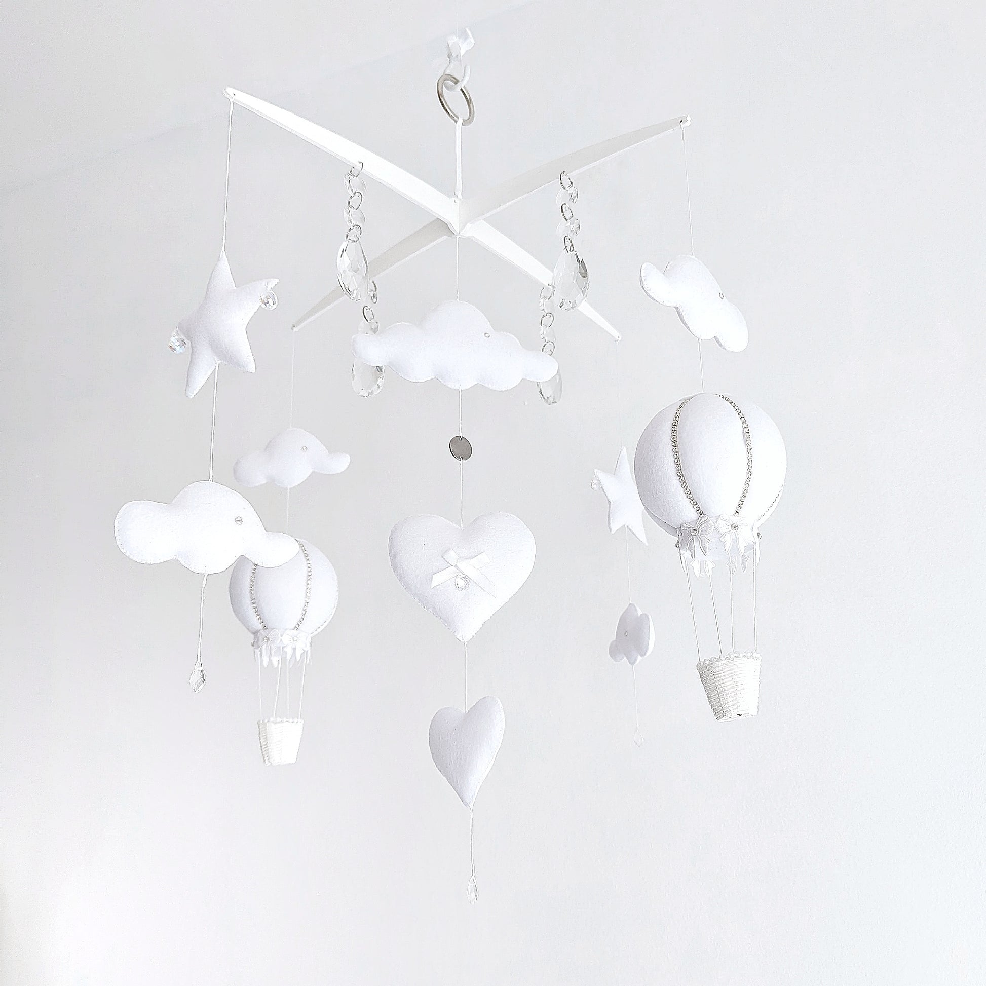 Elegant white nursery mobile featuring handcrafted hot air balloons, star details, and crystal drops for a soft sky-inspired look.