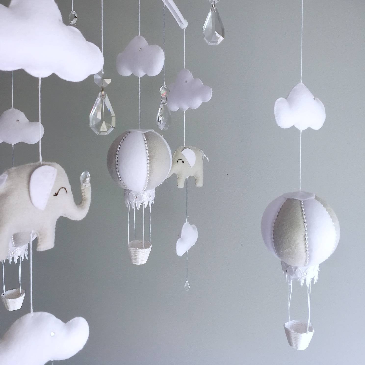Soft grey and white nursery mobile gently styled above a crib, made to bring a feeling of floating and calm to the space.