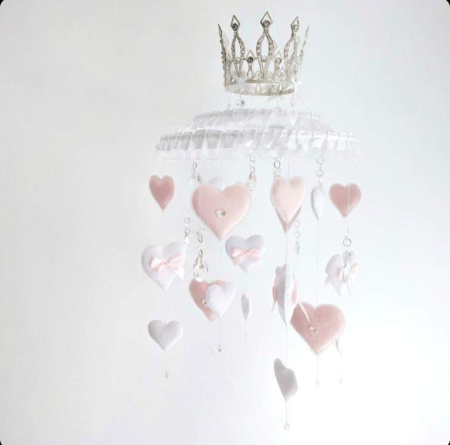 Princess-inspired baby mobile with ruffled trim, dangling hearts, and a regal crown centrepiece.

