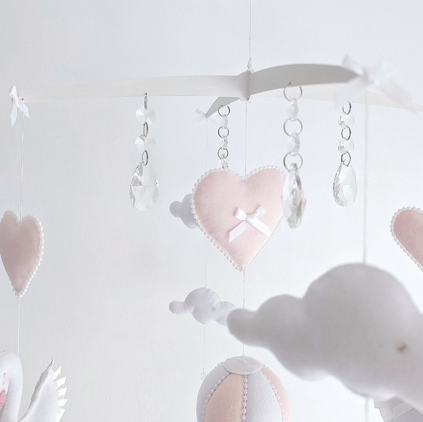  Refined swan wall hanging with a flower crown and trailing hearts, ideal for elegant nursery decor.
