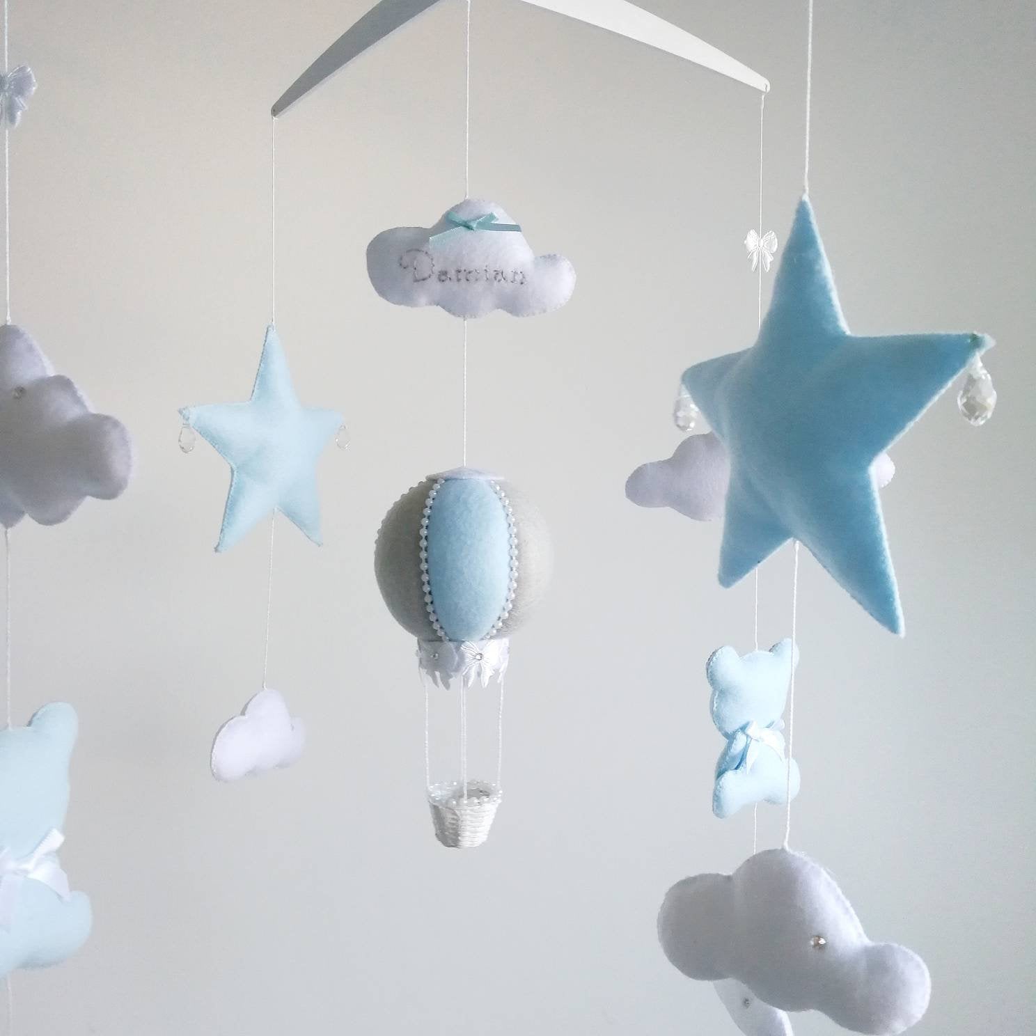 Close up of a blue star and soft white clouds from a dreamy handmade mobile for a baby boy nursery.