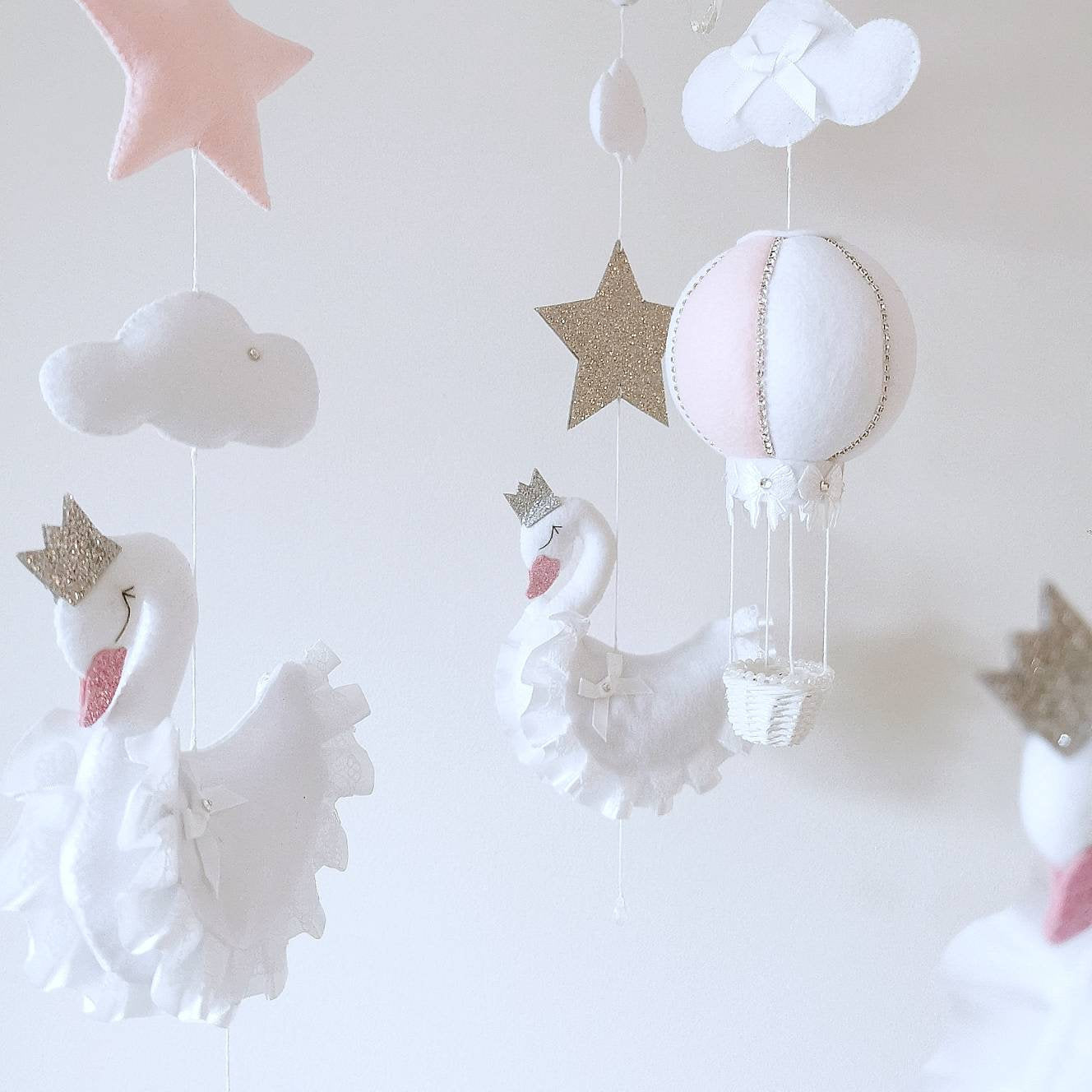 Close-up of a soft felt swan with ruffled wings and a sparkly crown, lovingly crafted for a gentle and elegant nursery feel

