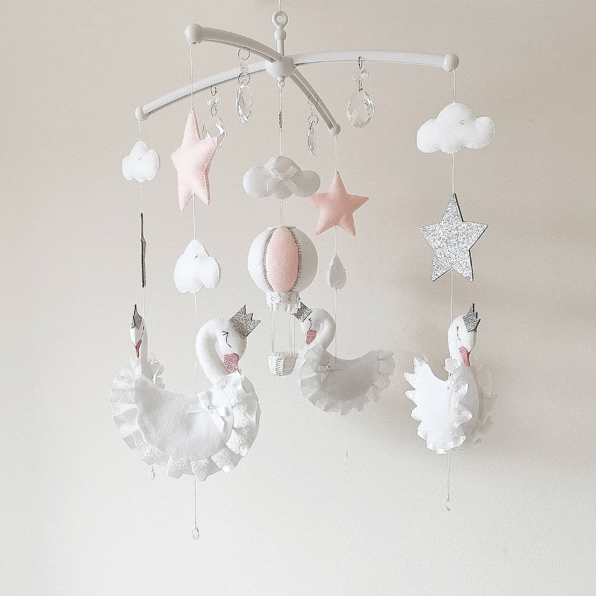 Handmade baby mobile with princess swans, soft pink stars, clouds and a blush balloon bringing magic to a baby girl’s nursery