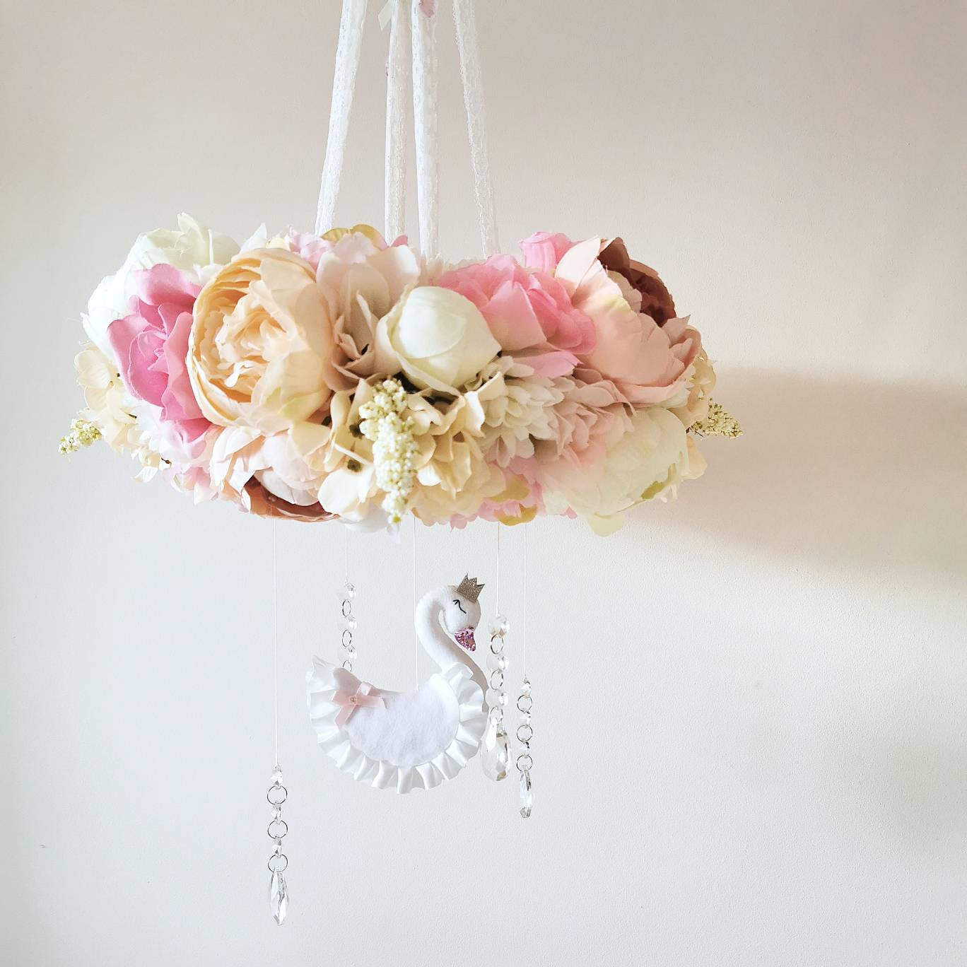 Looking up into a garden of blooms with a peaceful swan and crystal drops floating softly above a sleeping baby

